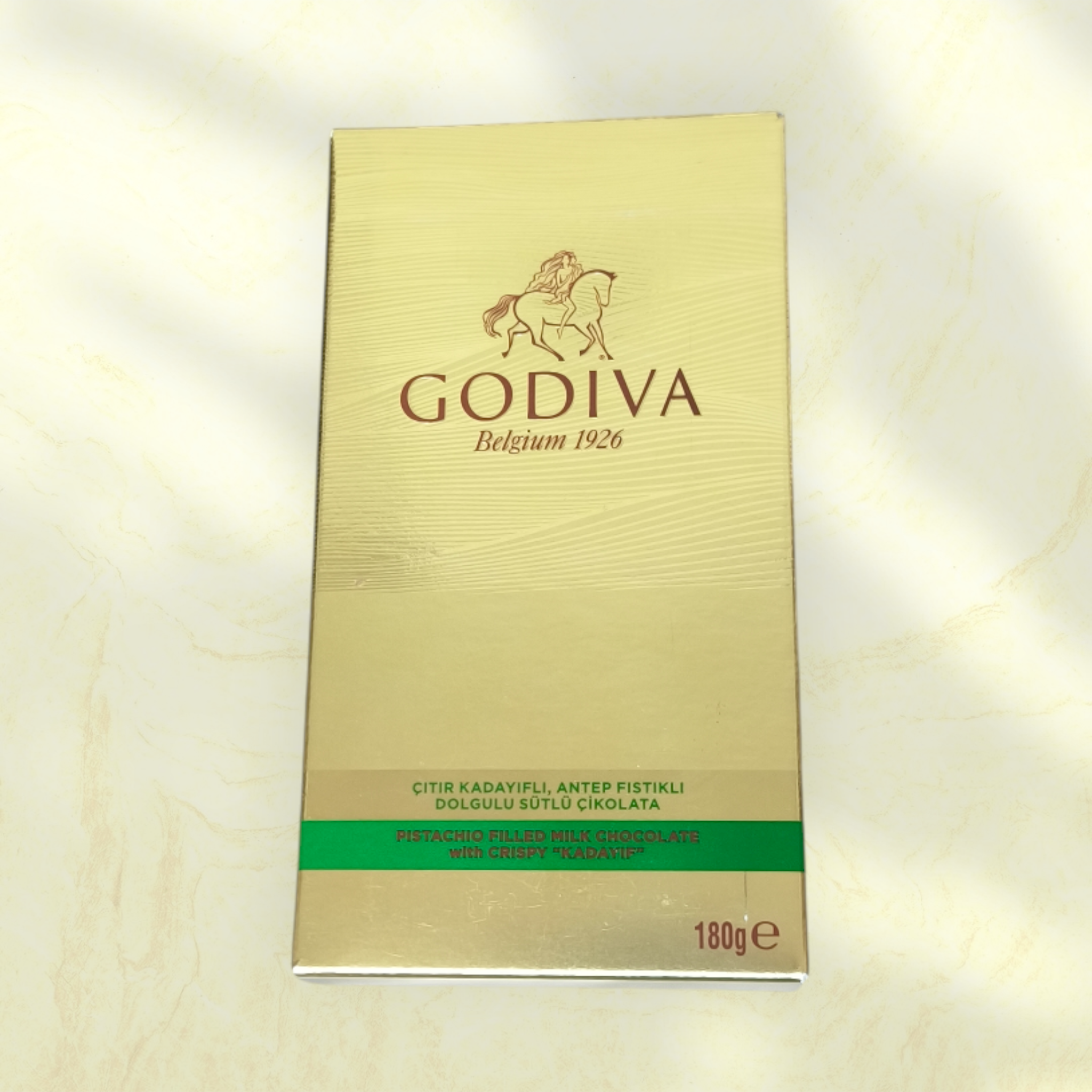 Gold Godiva chocolate box on a light beige background
