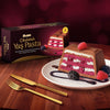 Slice of layered dessert on a plate with a box of Ulker Cikolatali Yas Pasta in the background. Ulker Milk Chocolate Cake with Velvety Red Velvet Base and Forest Berry Sauce – 13.9 oz (395 G)