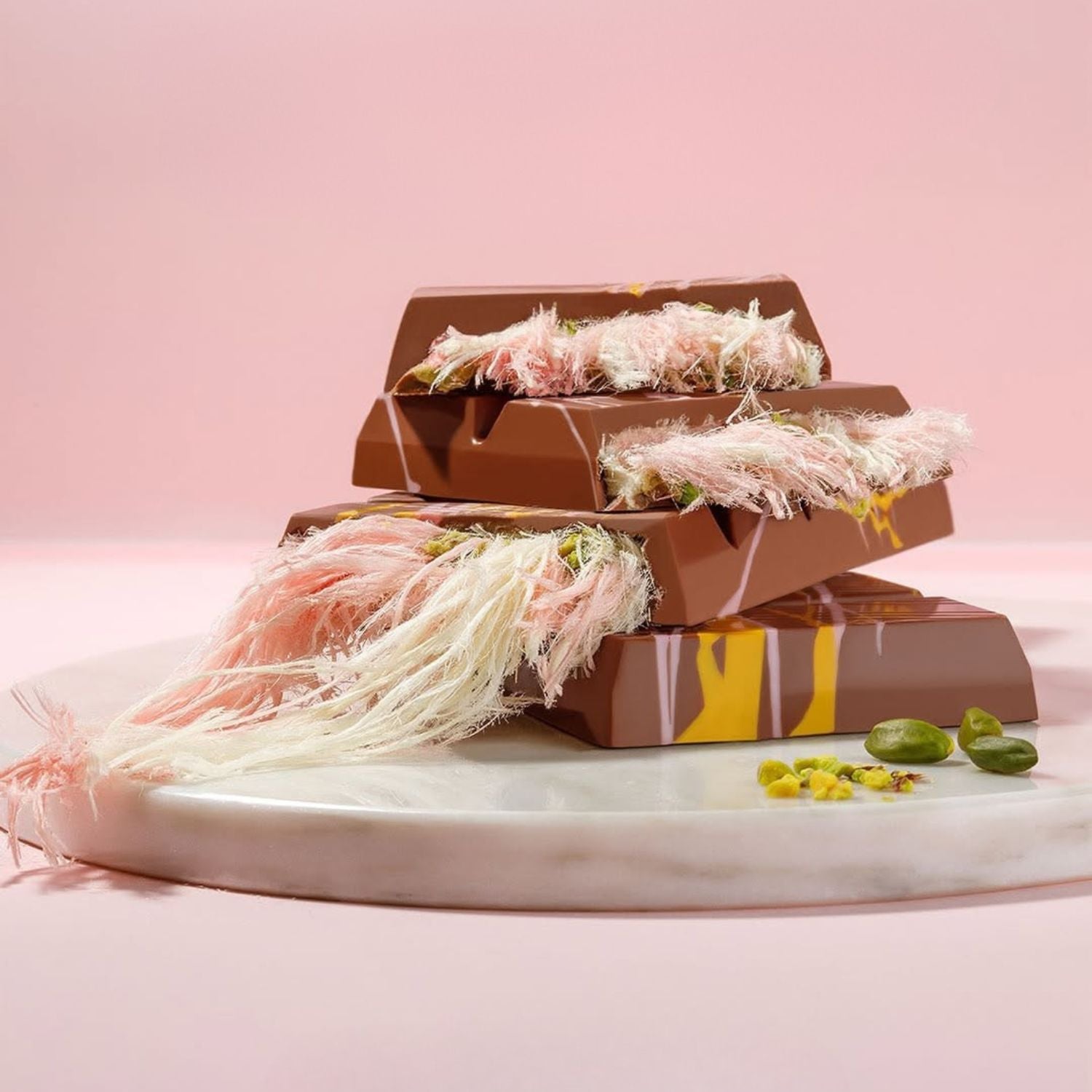 Angel Hair pink chocolate bars with decorative elements on a marble surface against a pink background