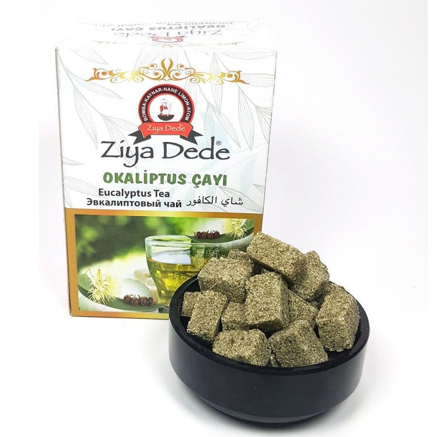 Ziya Dede Okaliptus Eucalyptus Tea packaging box next to a black bowl filled with dried green tea cubes on a white background.